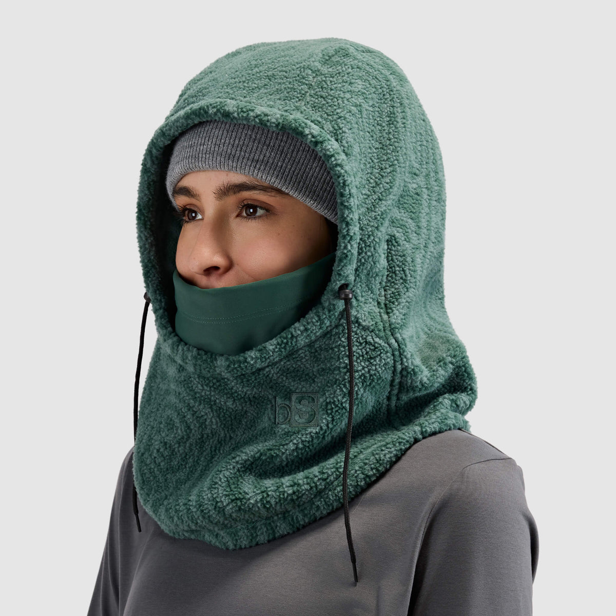 BlackStrap Caldera Hood Sherpa Fleece Overhood Inprint Obsidian worn by a woman wearing a beanie #color_inprint obsidian