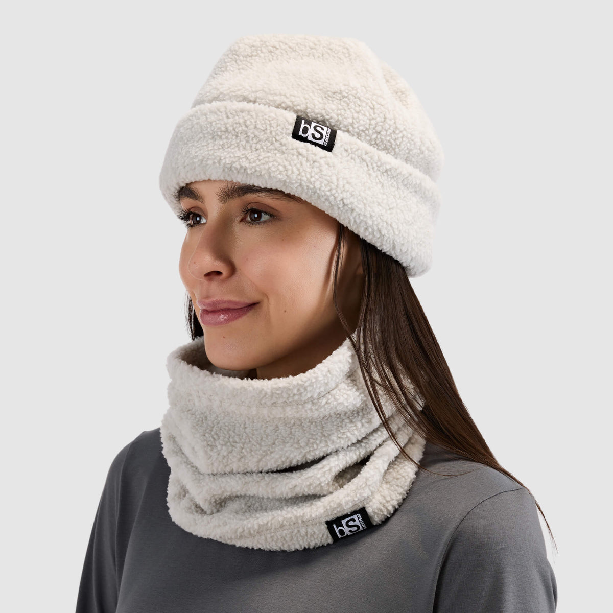 BlackStrap Caldera Sherpa Fleece Tube Neck Gaiter Inprint Ash worn by a woman with a beanie and worn around the neck like a scarf #color_inprint ash