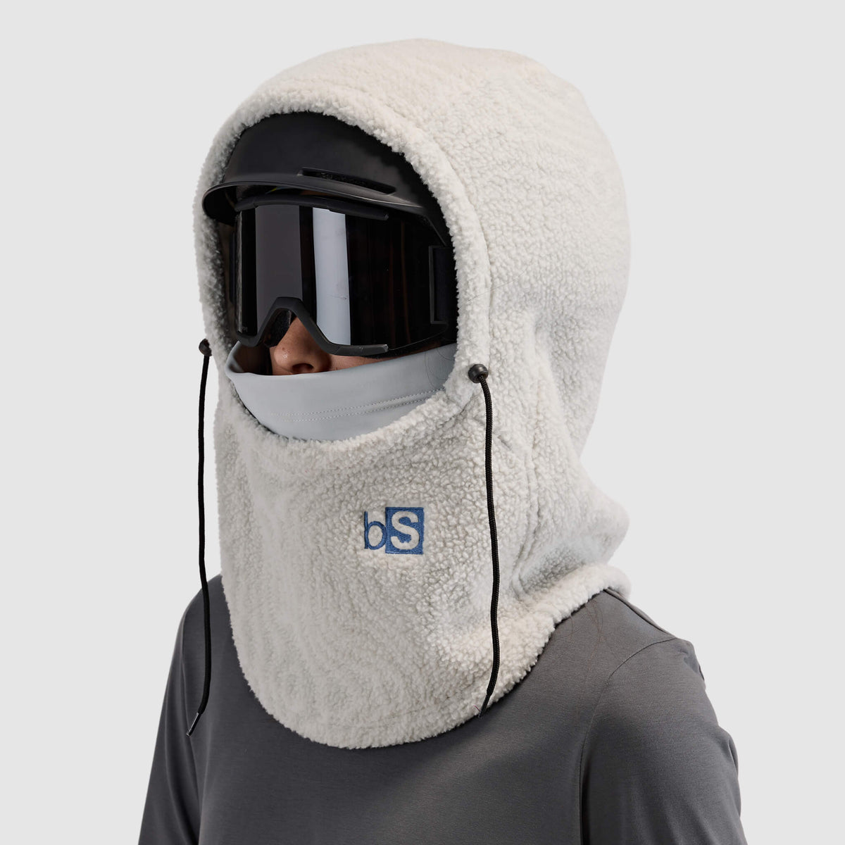 BlackStrap Caldera Hood Sherpa Fleece Overhood Inprint Ash worn by a woman wearing a helmet and ski goggles #color_inprint ash