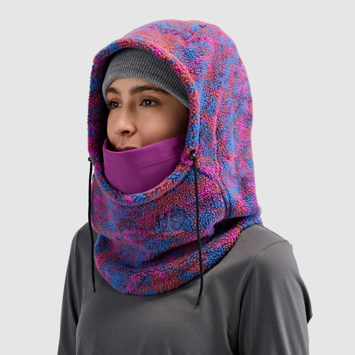 BlackStrap Caldera Hood Sherpa Fleece Overhood Pulse Currant worn by a woman wearing a beanie #color_pulse currant