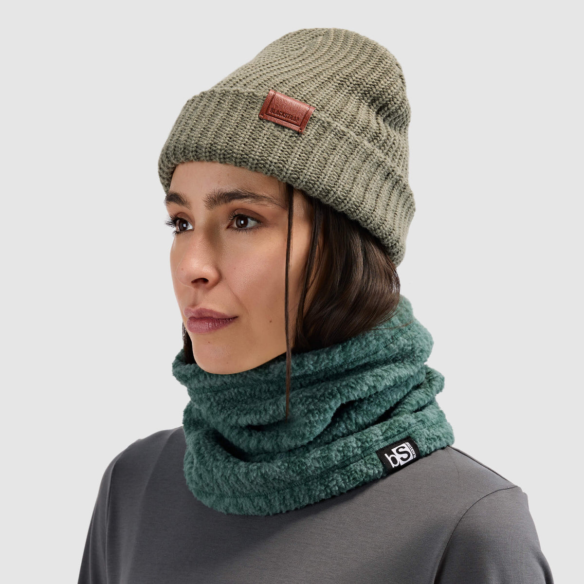 BlackStrap Caldera Sherpa Fleece Tube Neck Gaiter Inprint Obsidian worn by a woman with a beanie and worn around the neck like a scarf #color_inprint obsidian