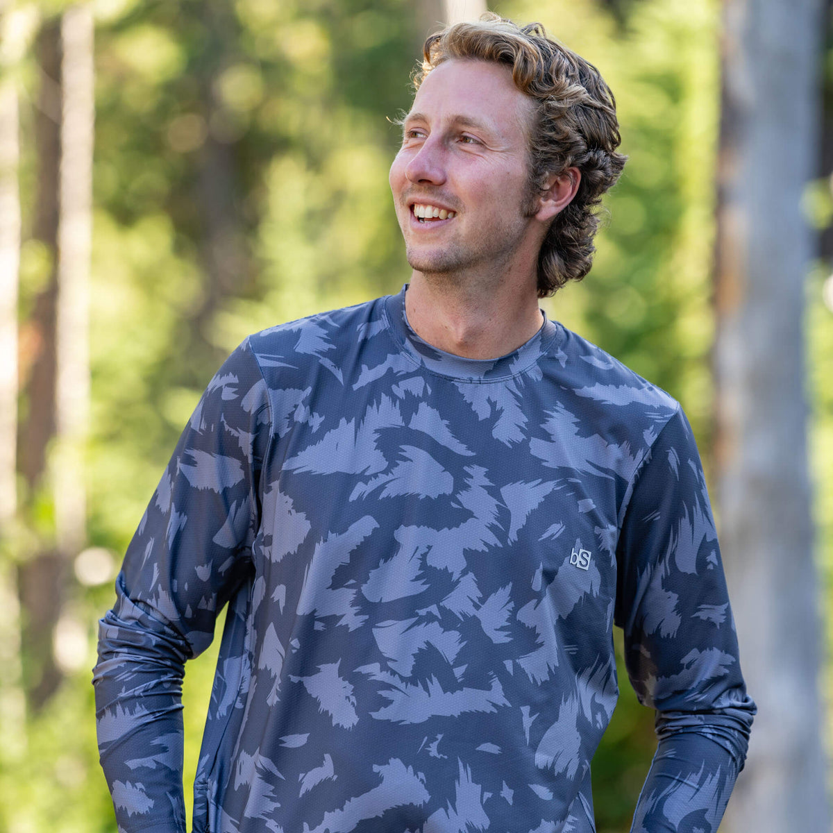 Close-up of a man on a forest trail wearing the BlackStrap Men's Voyage Crew Long Sleeve #color_slash smoldered