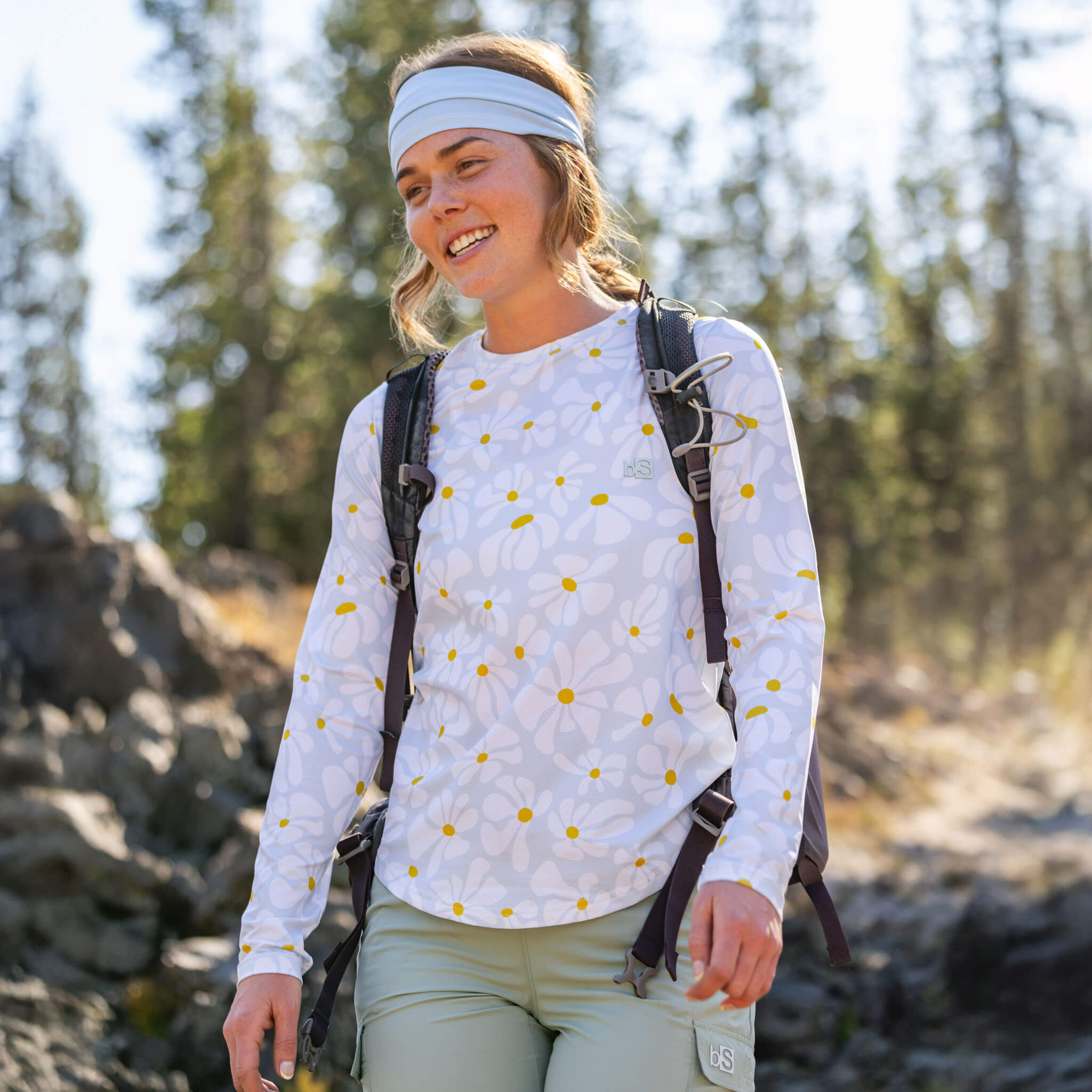 Woman hiking with a backpack on a rocky trail wearing the BlackStrap Women's Voyage Crew Long Sleeve #color_boho stratus 